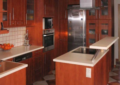 Diófa színű modern konyha középső szigettel, magas tárolókkal és inox páraelszívóval