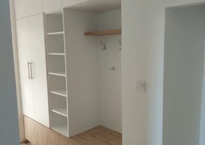 Mennyezetig érő fehér gardróbszekrény nyitott polcokkal és tölgyfa mintázatú alsó tárolókkal