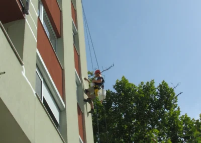 Ipari alpinista magas épület homlokzatán dolgozik kötéltechnikával