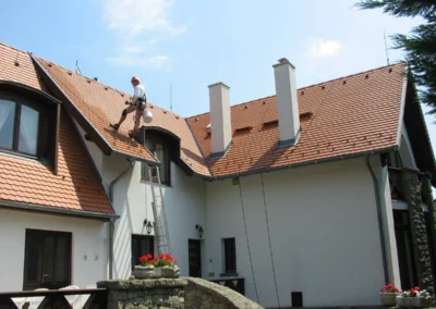 Ipari alpinista tetőn dolgozik családi házon, festési és karbantartási munkák