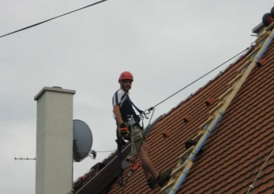 Ipari alpinista tetőn dolgozik létrával, magasban végzett karbantartás