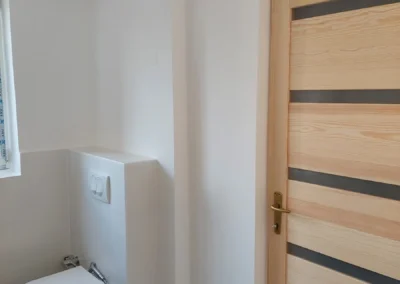 Minimalista fehér WC helyiség beépített tartállyal és falra szerelt vécécsészével
