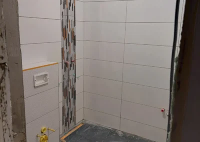 Modern fürdőszoba fehér falburkolattal és dekor csempe csíkkal